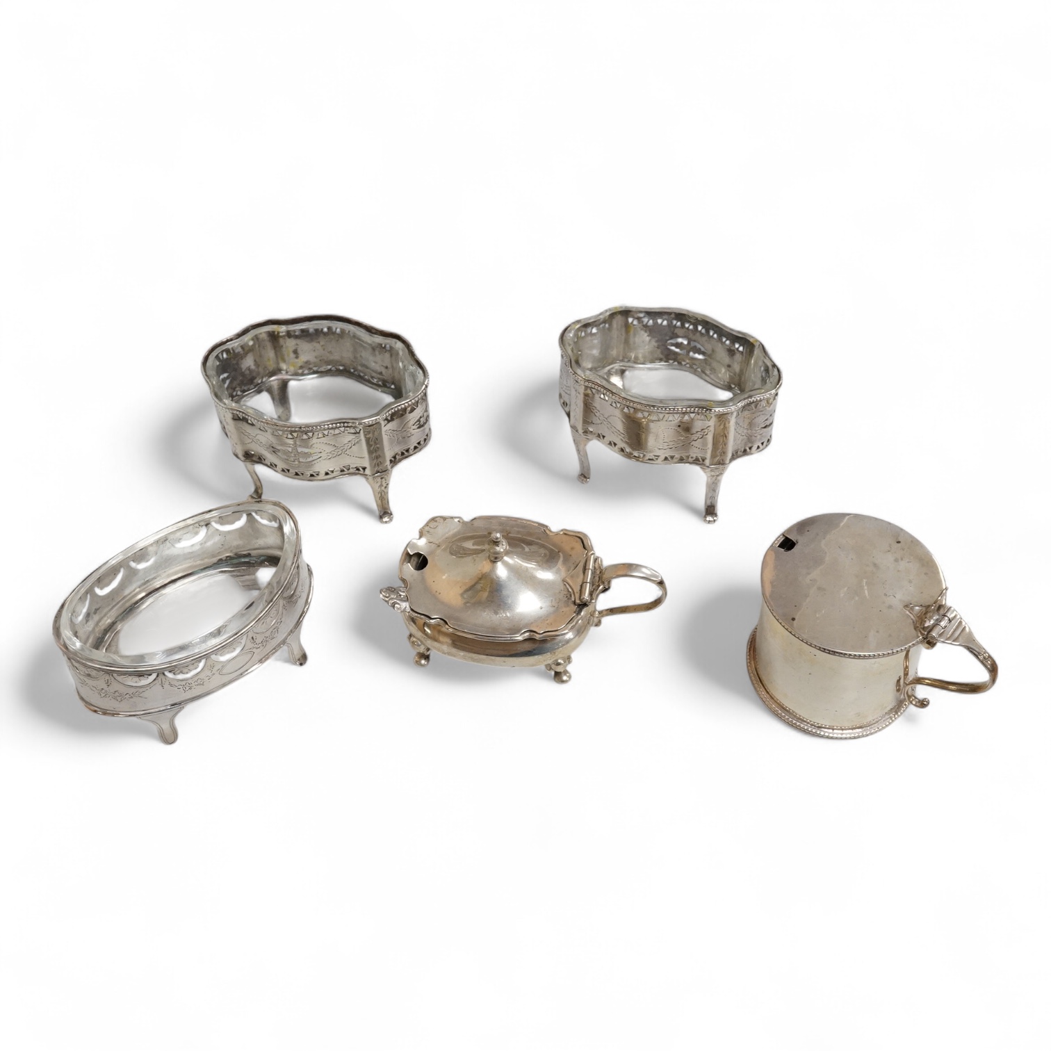 A pair of George III pierced silver shaped oval salts by Hester Bateman, London, 1783 (a.f.), with clear glass liners, together with one other George III silver oval salt, London, 1783 and two later silver mustard pots.
